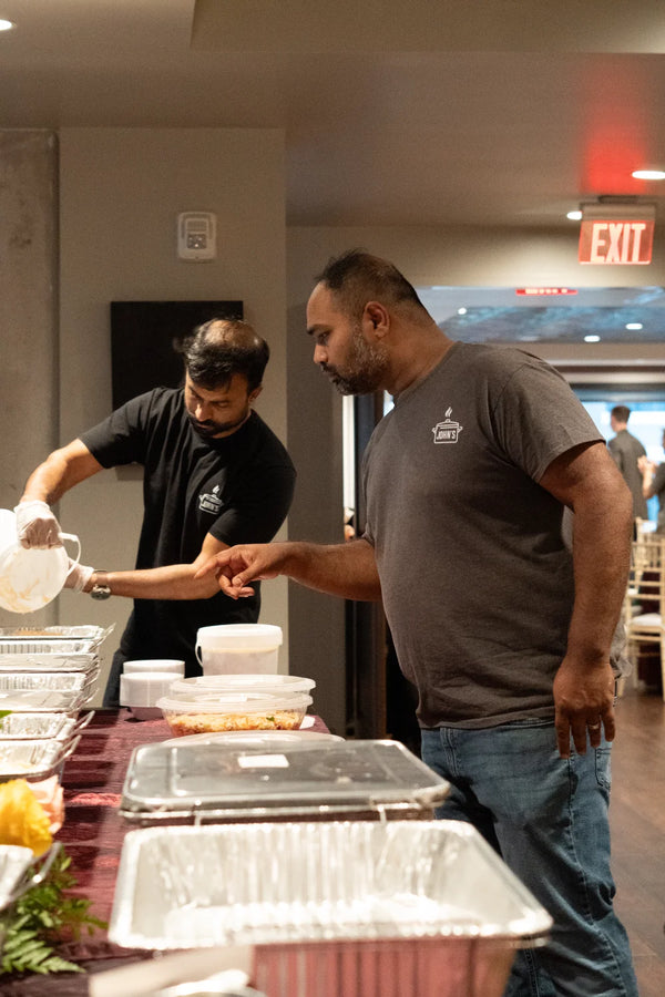 John's South Indian Kitchen staff preparing maroon cloth buffet line